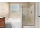Bright bathroom features a large soaking tub, a glass-enclosed shower, and a window for natural light at 18896 N Lariat Rd, Maricopa, AZ 85138