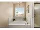 Close up of the bathtub showcasing marble-look tiling, natural light, and modern fixtures at 213 E Vaughn Ave, Gilbert, AZ 85234