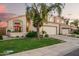 Charming two-story home with a three car garage, lush landscaping, and a lovely red umbrella on the front patio at 213 E Vaughn Ave, Gilbert, AZ 85234
