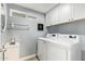 Bright laundry room featuring a modern washer and dryer, white cabinets, and neutral paint at 213 E Vaughn Ave, Gilbert, AZ 85234