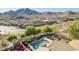 Scenic aerial shot of a backyard oasis featuring a pool, patio, and lush landscaping against a mountain backdrop at 2674 N Saide Ln, Buckeye, AZ 85396
