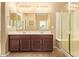 Bathroom with double sinks, large mirror, vanity with dark wood cabinets, and glass shower at 2674 N Saide Ln, Buckeye, AZ 85396