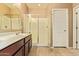Bright bathroom features double sinks, vanity with dark wood cabinets, shower with a glass door at 2674 N Saide Ln, Buckeye, AZ 85396