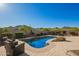 Beautiful backyard pool with mountain views, surrounding stone patio, and cozy outdoor seating area at 2674 N Saide Ln, Buckeye, AZ 85396