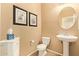 A cozy powder room featuring a pedestal sink, toilet, and decorative wall art at 2674 N Saide Ln, Buckeye, AZ 85396