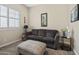 Comfortable bedroom with soft gray sofa, ottoman, and window with white shutters for ample sunlight at 28019 N 115 Pl, Scottsdale, AZ 85262