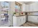 Cozy kitchen with white cabinetry, stainless appliances, stone backsplash and backyard views at 28019 N 115 Pl, Scottsdale, AZ 85262