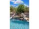 Inviting pool with a rock waterfall feature, surrounded by lush palm trees and meticulous landscaping at 28019 N 115 Pl, Scottsdale, AZ 85262