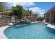 Tranquil pool with rock waterfall feature and cozy patio seating for relaxation and outdoor enjoyment at 28019 N 115 Pl, Scottsdale, AZ 85262