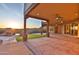 Spacious covered back patio with ceiling fans and sunset view overlooking a landscaped yard and pool at 2918 N 90Th St, Mesa, AZ 85207