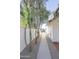 Side yard featuring a sidewalk, trees, a wall and decorative rock alongside a home with white siding at 3371 W Grandview Rd, Phoenix, AZ 85053