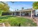 View of the backyard with a large grassy area, palm trees and a patio at 3411 E Sells Dr, Phoenix, AZ 85018