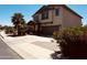 Exterior front-side view of a two-story tan home with desert landscaping and a private driveway at 41143 W Rio Bravo Dr, Maricopa, AZ 85138