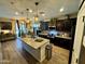 Well-lit kitchen featuring a large island with granite countertops, dark cabinets, and stainless steel appliances at 41143 W Rio Bravo Dr, Maricopa, AZ 85138