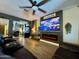 Comfortable living room with wood floors, leather sectional sofa, and mounted TV with a fireplace feature at 41143 W Rio Bravo Dr, Maricopa, AZ 85138
