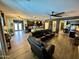 Spacious living room featuring wood-look flooring, a dark leather sofa, and views of the kitchen and dining room at 41143 W Rio Bravo Dr, Maricopa, AZ 85138