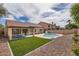 Backyard featuring artificial turf, a refreshing pool, desert landscaping, and a covered patio seating area at 4346 E Prickly Pear Trl, Phoenix, AZ 85050