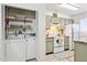Cozy kitchen, with laundry area, showcasing sage green cabinets and white appliances, with tiled floors and natural light at 510 N Alma School Rd # 139, Mesa, AZ 85201