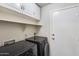 This laundry room features dark colored appliances, white cabinets, and white door at 5729 S 21St Ter, Phoenix, AZ 85040