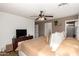Spacious main bedroom with ceiling fan, wood-look floors, large television, and ensuite bathroom at 6343 W Sophie Ln, Laveen, AZ 85339