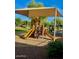 A playground with swings, slides, and a protective overhead canvas in a park-like setting at 6343 W Sophie Ln, Laveen, AZ 85339