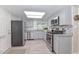 Well-lit kitchen with stainless appliances, gray cabinets, granite countertops, and wood-look flooring at 8930 W Sells Dr, Phoenix, AZ 85037