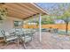 Comfortable covered patio featuring a dining area and additional seating surrounded by lush landscaping at 8930 W Sells Dr, Phoenix, AZ 85037