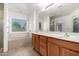 Bright bathroom with double sinks, wood cabinetry, bathtub, and a large mirror at 1071 E Chelsea Dr, San Tan Valley, AZ 85140