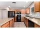 Modern kitchen featuring an island, black appliances, wood cabinets, and tile flooring at 1071 E Chelsea Dr, San Tan Valley, AZ 85140