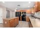 A spacious kitchen featuring an island, black appliances, wood cabinets, and tile flooring at 1071 E Chelsea Dr, San Tan Valley, AZ 85140