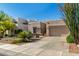 A tan home with xeriscaping and native plants, a stone facade, and an attached two-car garage at 10869 E Hedgehog Pl, Scottsdale, AZ 85262