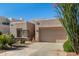 A tan home with xeriscaping and native plants, a stone facade, and an attached two-car garage at 10869 E Hedgehog Pl, Scottsdale, AZ 85262