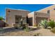 A tan home with xeriscaping and native plants, a stone facade, and an attached two-car garage at 10869 E Hedgehog Pl, Scottsdale, AZ 85262