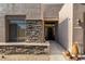 A tan home with a stone facade surrounding the entry, desert plants, and a light fixture at 10869 E Hedgehog Pl, Scottsdale, AZ 85262