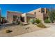 A tan home with xeriscaping and native plants, a stone facade, and an attached two-car garage at 10869 E Hedgehog Pl, Scottsdale, AZ 85262