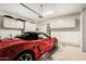 Garage featuring built-in white cabinets and a red convertible at 10869 E Hedgehog Pl, Scottsdale, AZ 85262