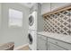 This is a modern laundry room with stackable washer and dryer and patterned backsplash at 1140 E Vermont Dr, Gilbert, AZ 85295