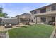 Spacious backyard featuring artificial grass, a dining set, fire pit area and desert landscaping at 11915 W Charter Oak Rd, El Mirage, AZ 85335