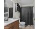 Well-lit bathroom featuring a vanity with a wood cabinet, toilet, and a shower with a dark shower curtain at 11915 W Charter Oak Rd, El Mirage, AZ 85335