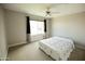 A simple bedroom with a ceiling fan, window with curtains, carpet, and bed covered by a white quilt at 1374 N Alexis Dr, Gilbert, AZ 85234