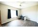 A brightly lit bedroom featuring a ceiling fan, dark curtains, and durable wood flooring at 1374 N Alexis Dr, Gilbert, AZ 85234