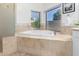 Soaking tub with tile surround under large windows offering natural light and views at 15215 S 20Th Pl, Phoenix, AZ 85048