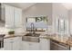 Bright kitchen with a stainless steel farmhouse sink, granite countertops, and white cabinets at 15215 S 20Th Pl, Phoenix, AZ 85048