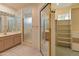 Bathroom with a double sink vanity, glass block window, shower and mirrored closet in a neutral color palette at 15610 N 98Th Ave # 26, Sun City, AZ 85351
