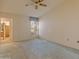 Cozy bedroom with a ceiling fan, window with shutters, light carpet, and an ensuite bathroom at 15610 N 98Th Ave # 26, Sun City, AZ 85351