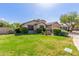 Attractive home with mature desert landscaping, a green lawn, and a neutral-colored exterior at 16605 W Pierce St, Goodyear, AZ 85338