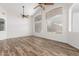 Bright living room featuring wood-look flooring, ceiling fans, and large windows with blinds at 16605 W Pierce St, Goodyear, AZ 85338