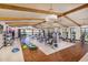 Bright and airy gym with a variety of modern exercise equipment, beamed ceilings, and views of the lake at 17375 W Whispering Wind Rd, Surprise, AZ 85387