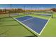 Well-maintained blue pickleball courts with green surfacing, black fencing, and lights ready for a game at 17375 W Whispering Wind Rd, Surprise, AZ 85387