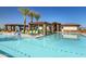Sparkling community pool with lounge chairs, shaded pergolas, and swaying palm trees under a clear blue sky at 17375 W Whispering Wind Rd, Surprise, AZ 85387